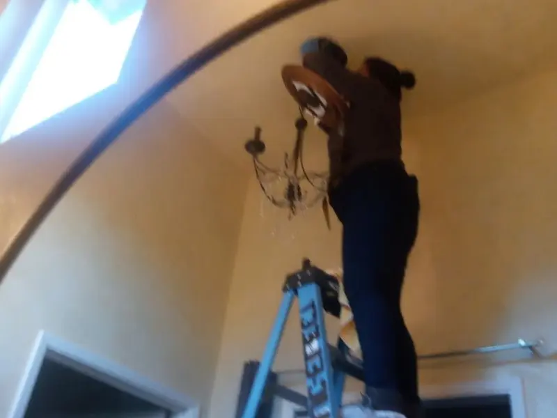 Electrician installing a chandelier in a Holland residence